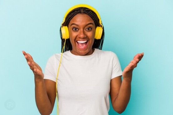 A cheerful young black lady listening to music from her headphone. 